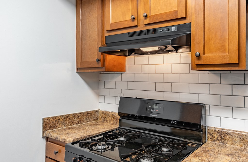 a kitchen with a stove and microwave and wooden cabinets