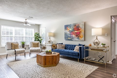 A living room with a blue couch, a wooden coffee table, and a painting on the wall.