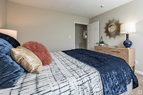 A bedroom with a bed, nightstand, and lamp.
