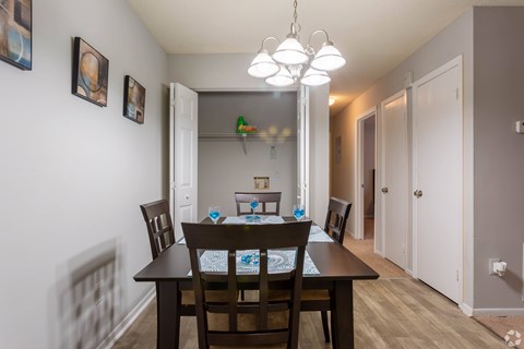 A dining room with a table set for two and a chandelier hanging from the ceiling.