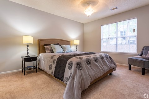 A bedroom with a large bed and two lamps.
