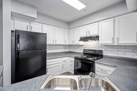 a kitchen with white cabinets and black appliances