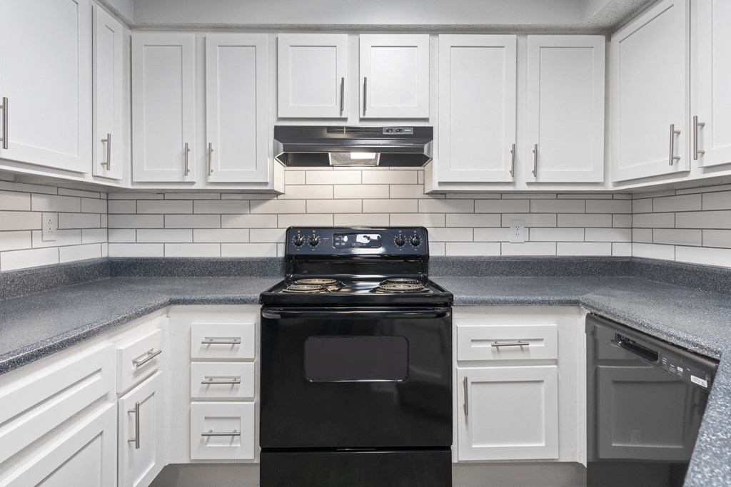 a kitchen with white cabinets and a black stove