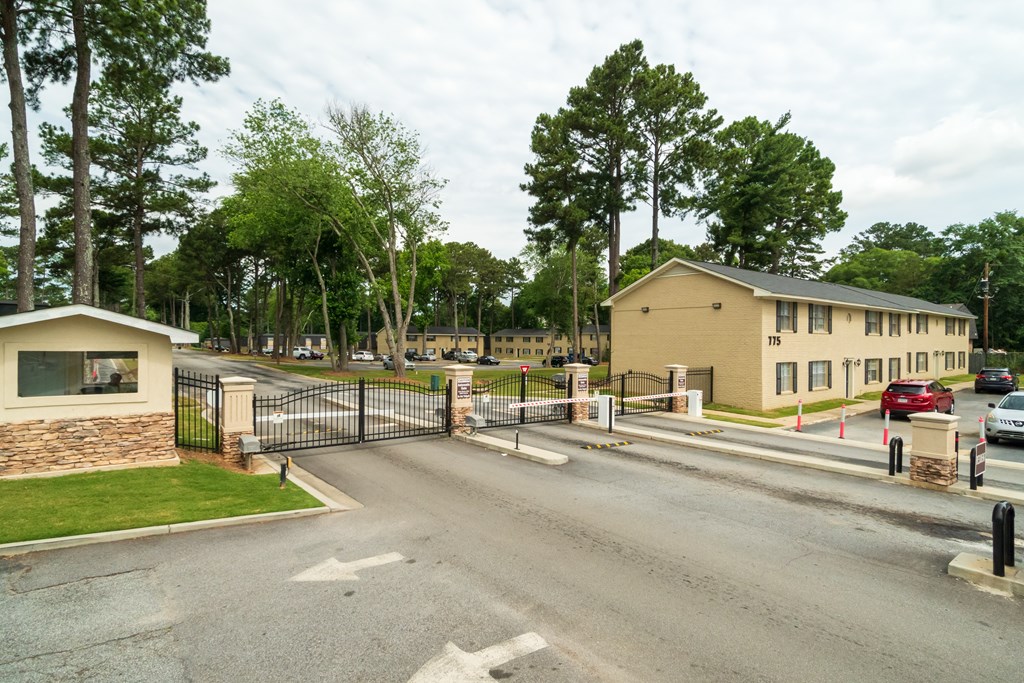 A gated entrance to a residential area with houses and trees.