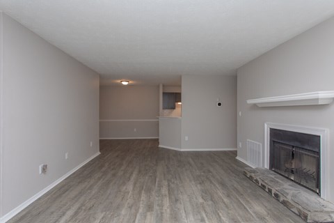 A large, empty room with a fireplace and wood flooring.