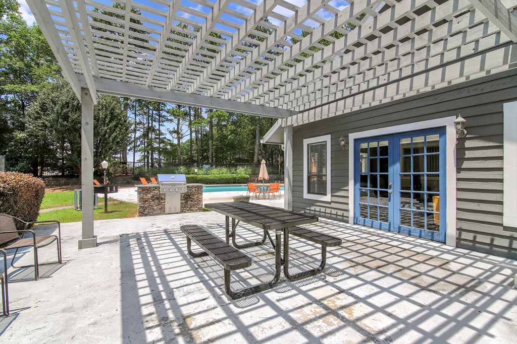 A patio with a table and chairs under a white pergola.