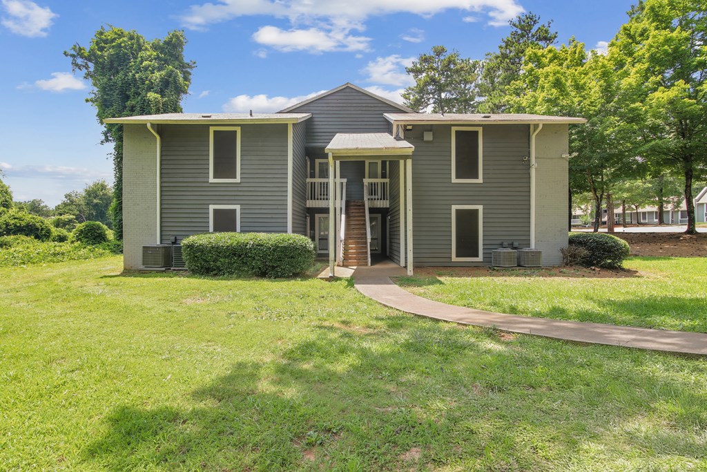 A grey two-story house with a green lawn in front.