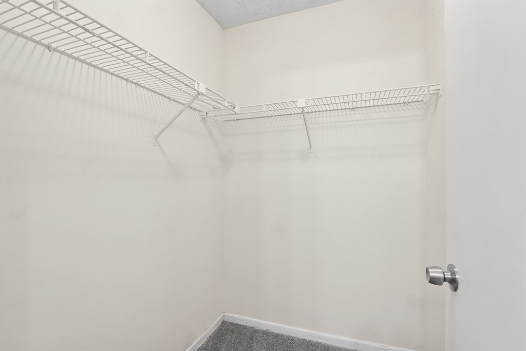 A white closet with a metal rack and a door.