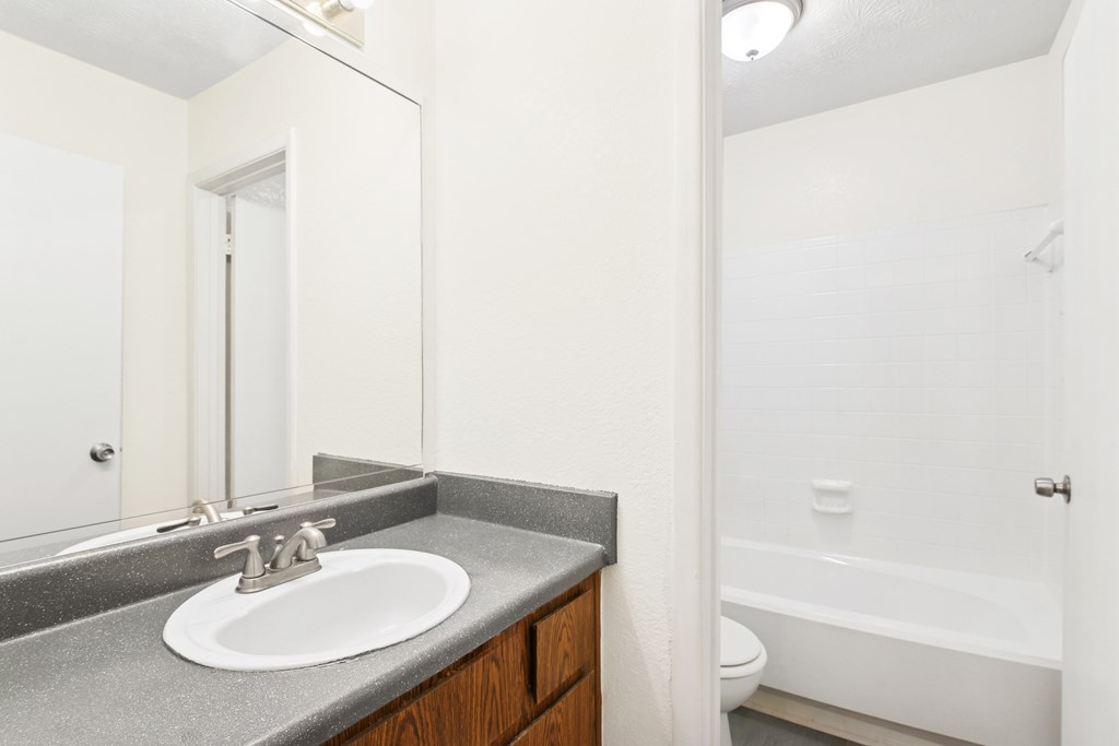 A bathroom with a sink, mirror, and bathtub.
