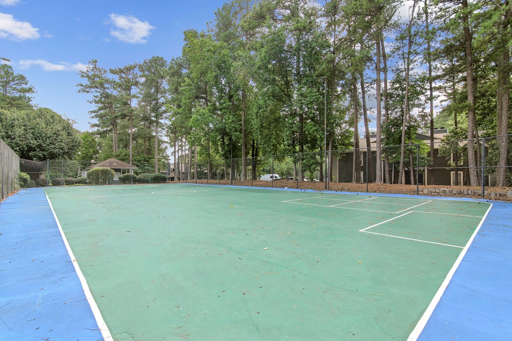 A tennis court surrounded by trees.