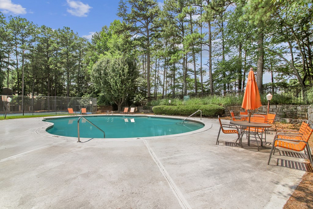 A pool surrounded by orange chairs and umbrellas.