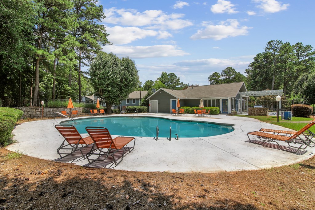 A pool with a few chairs around it.