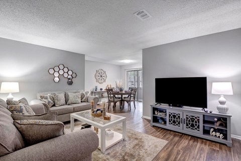 A living room with a grey couch, a white coffee table, and a black television.
