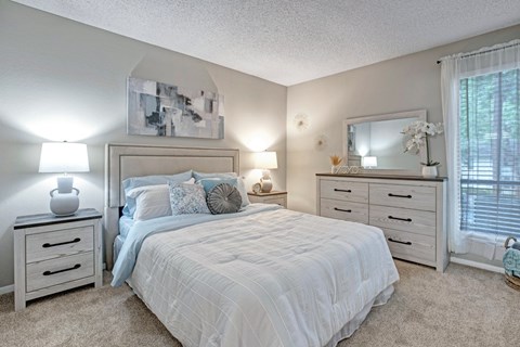A bedroom with a bed, nightstands, and a mirror.