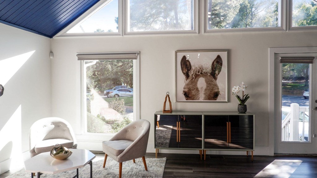 a living room with a large window and a painting of a horse