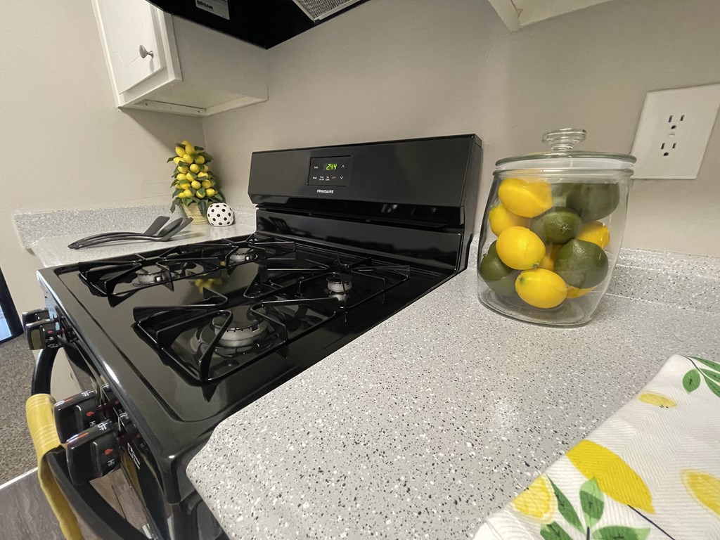 a kitchen with a stove and a glass jar of lemons