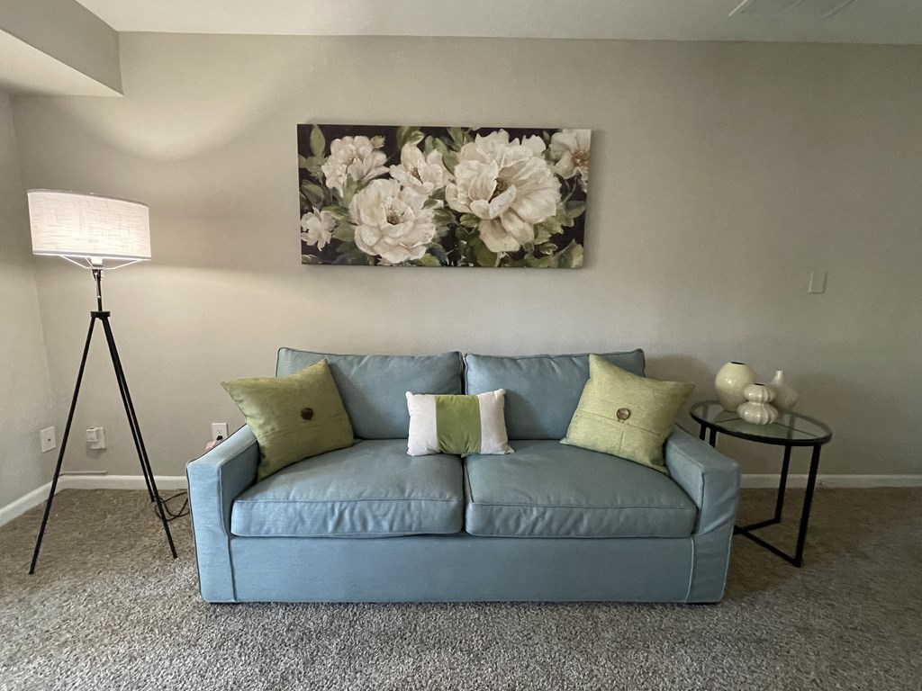 a living room with a couch and a painting of flowers