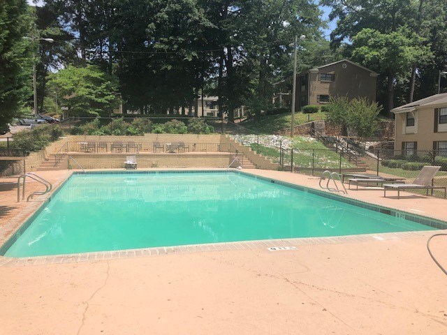 A small pool surrounded by a fence and trees.