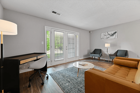 A living room with a brown sofa and a grey rug.