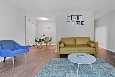 A living room with a blue chair, a yellow couch, and a white coffee table.