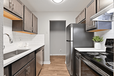 A kitchen with a black refrigerator and stove top oven.
