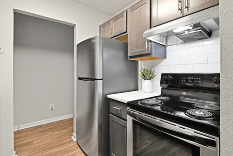 A kitchen with a black stove top oven and a silver refrigerator.