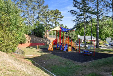 A playground with a red slide and a blue and yellow swing set.