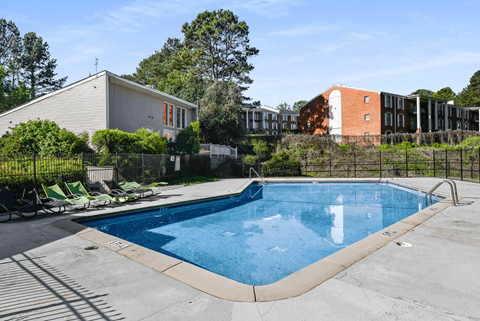 A swimming pool surrounded by a fence and chairs.