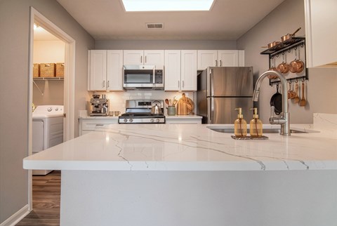 A modern kitchen with a white countertop and stainless steel appliances.