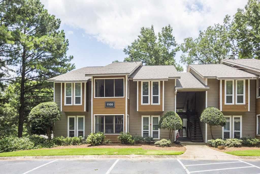 the front of a brown house with a lawn and trees
