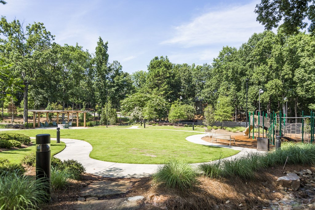 a park with green grass and a playground and trees