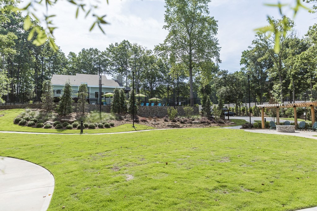 a park with grass and trees and a building in the background