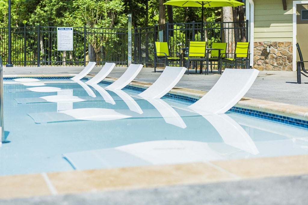 a swimming pool with three white chairs in it