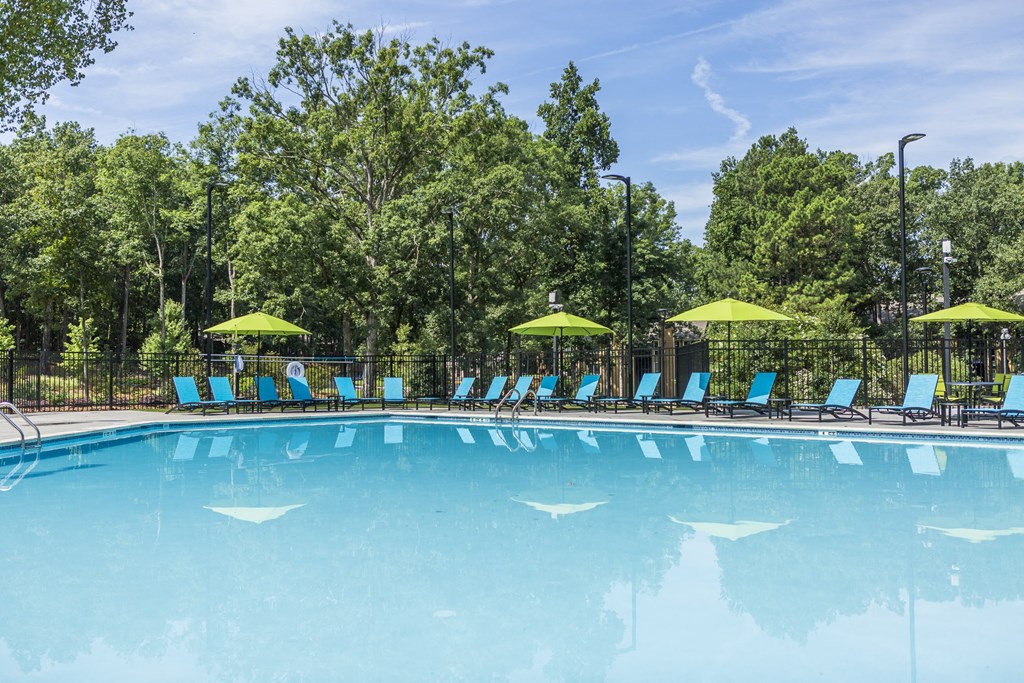 a swimming pool with blue lounge chairs and yellow umbrellas