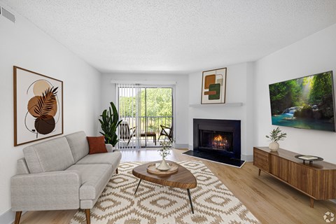 A living room with a grey couch, a coffee table, a fireplace, and a painting on the wall.