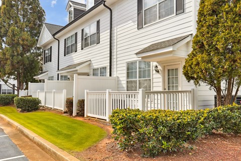 A white house with a black roof and a white fence.