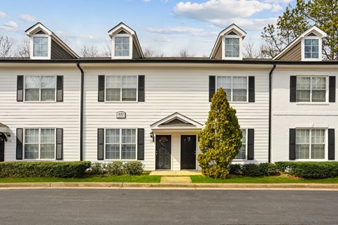 A white house with black shutters and a black door.