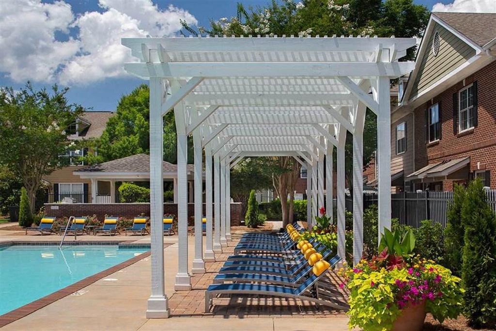 a pool with blue lounge chairs under a white shade