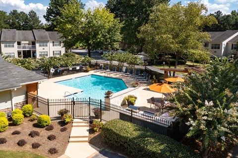 A pool surrounded by a black fence and trees.