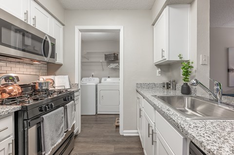 A kitchen with a black stove top oven and white cabinets.