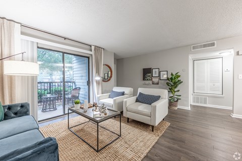 A living room with a blue couch and a glass table.