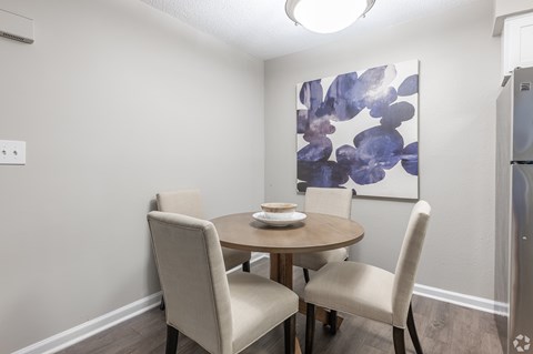 A dining room with a round table and four chairs.