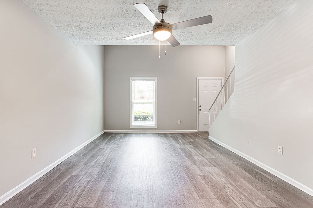 an empty living room with a ceiling fan and wood floors