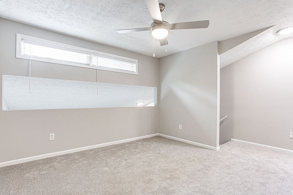 an empty bedroom with a ceiling fan and a window