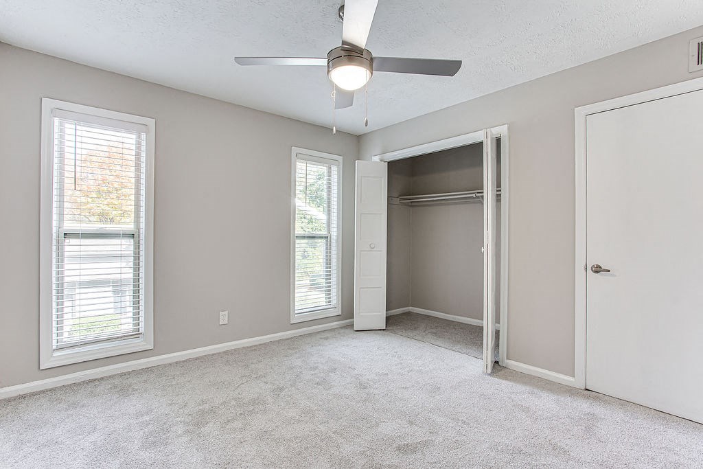 an empty bedroom with a ceiling fan and a closet