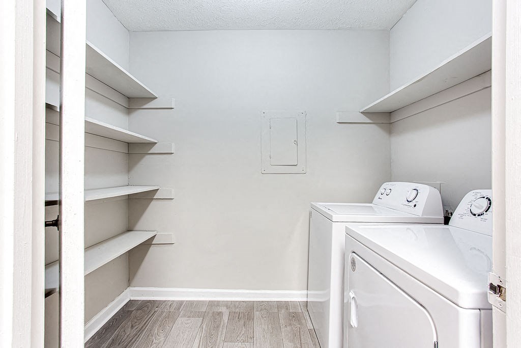 a washer and dryer in a white laundry room with shelves