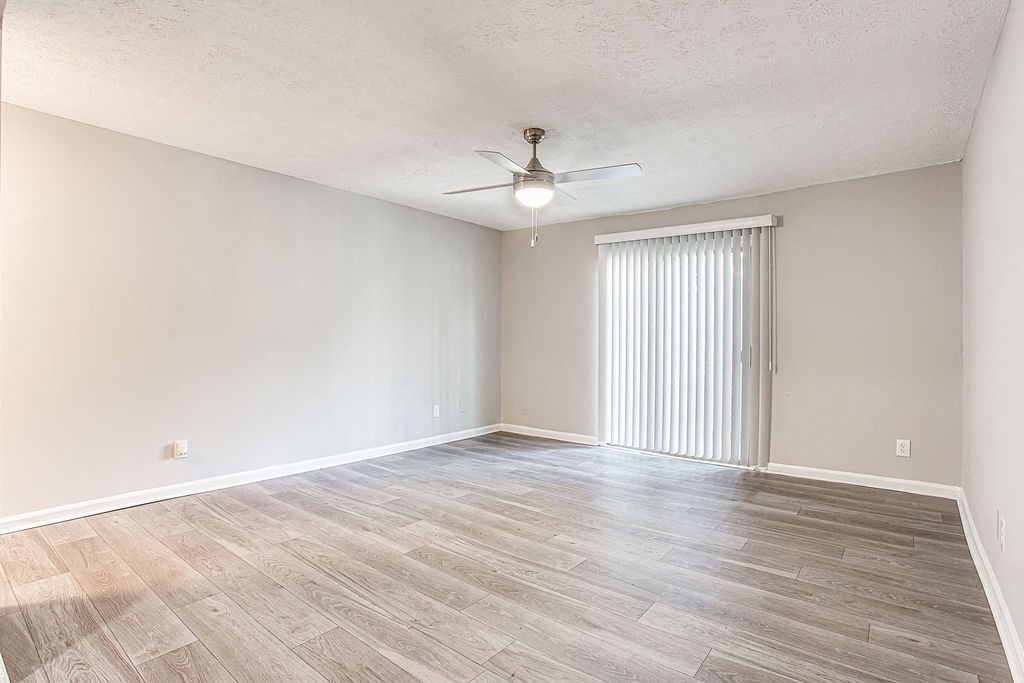 an empty living room with wood flooring and a ceiling fan