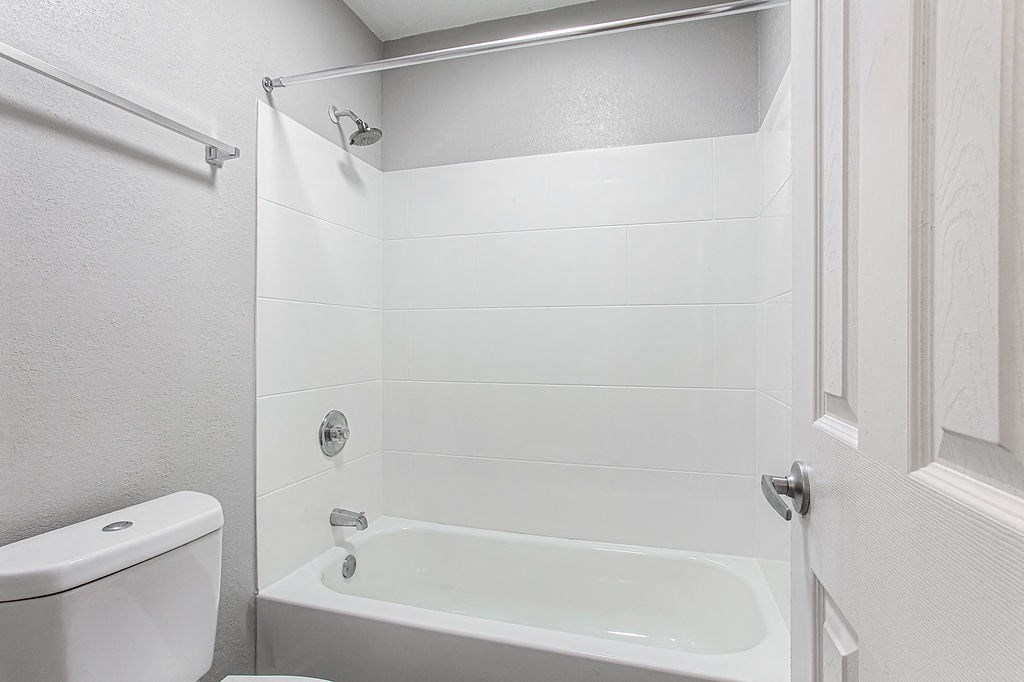 a white bathroom with a shower and a toilet