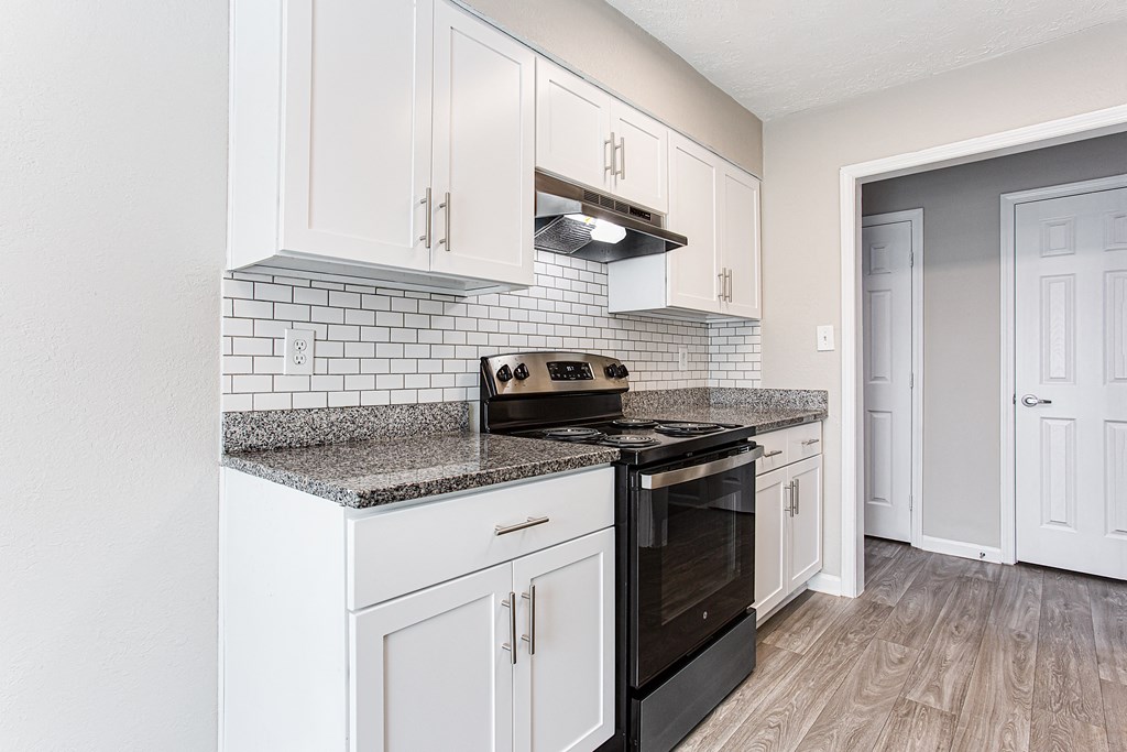 a renovated kitchen with white cabinets and a black stove