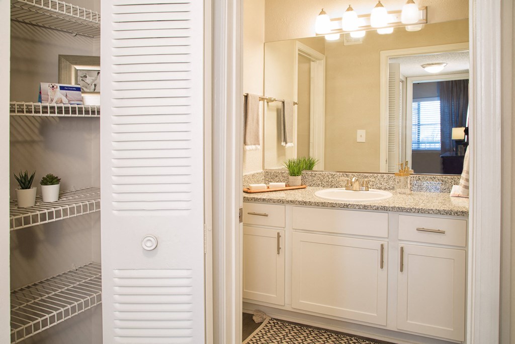 a bathroom with white cabinets and a sink and a mirror